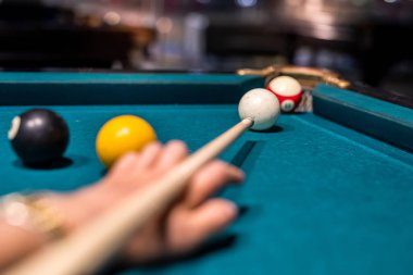 Kadın eli yeşil bilardo masasına bilardo topu doğrultuyor. Yaşam biçimi