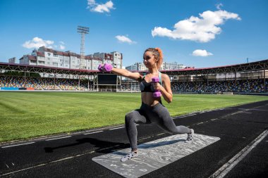 Esneme hareketleri yapan sportif bir kadın ya da stadyum pistinde yoga egzersizi yapan. Esneklik kavramı