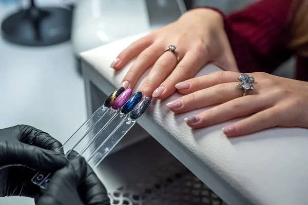 a professional nail extension master selects the color for his client during the epidemic. Manicure concept