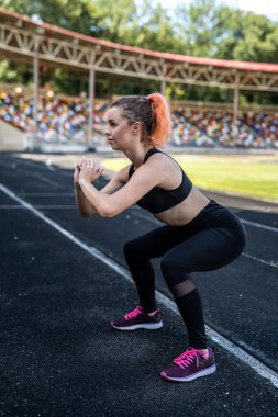 Esneme hareketleri yapan sportif bir kadın ya da stadyum pistinde yoga egzersizi yapan. Esneklik kavramı