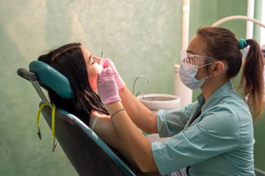 Doktor raporunda dişçi koltuğunda oturan genç kadın.