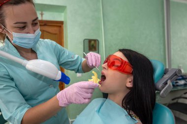 Kadın bir hastayla beyazlatma prosedürüne hazırlanan dişçi.