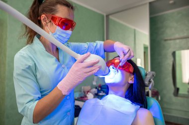 Diş hekimi olan kadın stomatologla beyazlatma prosedürü uyguluyor.