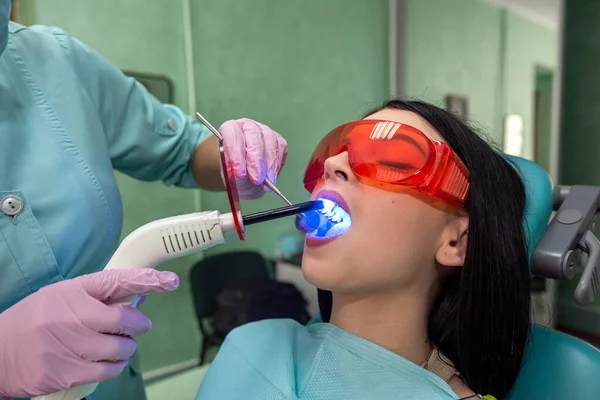 女性歯科医はUvランプで歯科患者の充填を行います 歯のホワイトニング手順 — ストック写真