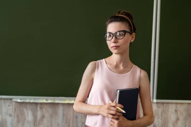 Güzel öğretmen boş okul tahtasının yanında yeni bir ders açıkladı, metin için kopyalama alanı