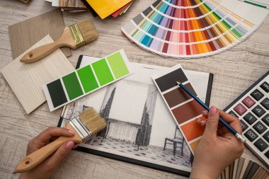 Kadın iç mimar, ofiste ev çizimi ile çalışarak paletten renk seçer