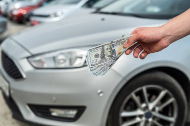 Yeni modern araba almak için para tutan bir adam. Ödeme