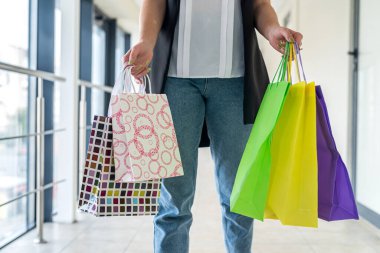 Alışveriş merkezinin içinde alışveriş torbaları olan genç bir kadın. Kara Cuma. Satış ve indirimler 