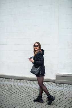 Güzel esmer, klasik siyah elbiseli, havalı bir şehrin sokaklarında. Şehirdeki kadın kavramı.