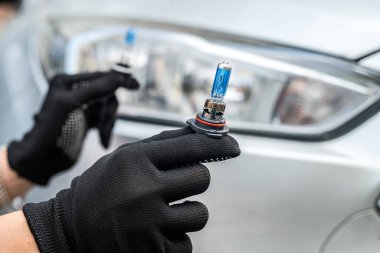 Araba servisi elemanları halojen h7 lambasını tamir etmek ya da farlarını değiştirmek için tutuyor.