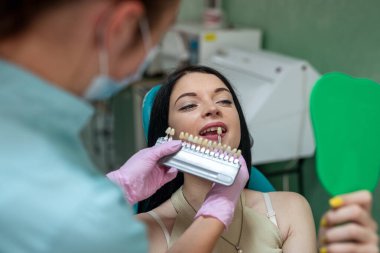 Diş hekimi, hastanın dişini diş hekimliğindeki renk örneğiyle karşılaştırıyor.