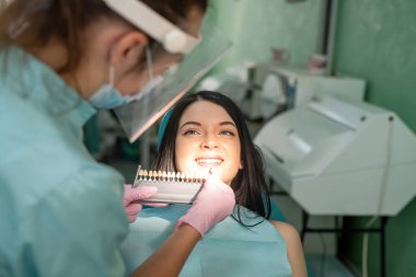 Diş hekimi, hastanın dişini diş hekimliğindeki renk örneğiyle karşılaştırıyor.