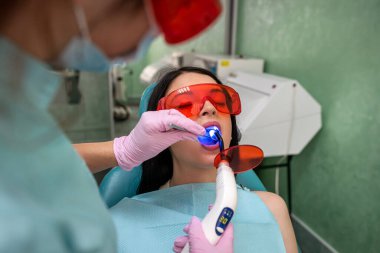 Diş hekimliğinde ultraviyole lambalı diş hekimi hastayı beyazlatıyor.