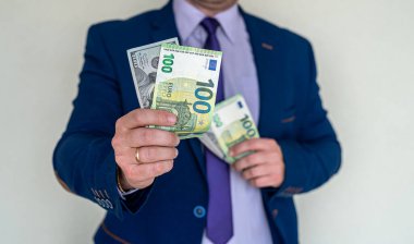 Avro ve dolar tutan mavi takım elbiseli bir adam. yatırım kavramı