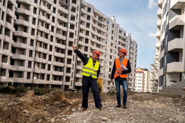 Yakışıklı, güçlü, özel elbiseli bir işçi eve el attığını ve diğerinin yakınlarda durduğunu gösteriyor. İnşaat konsepti