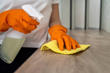 Turuncu eldivenli güzel kadın elleri mutfak yüzeyini tozdan temizler. Temizlik kavramı