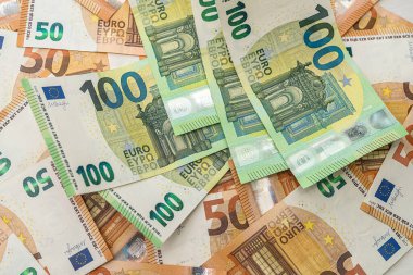 Masaya 50 avroluk yeni turuncu banknotlar saçıldı ve bunların üzerinde 100 avroluk akarsu banknotlar bulunuyor. Lüks konsepti. Para birimi kavramı