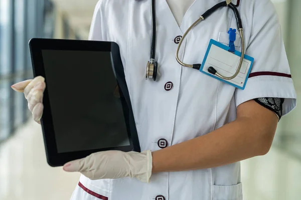 young beautiful nurse stands in the hallway with a stethoscope and a tablet. Medicine concept