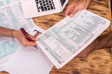 İşteki iki çalışan ofis masasında 1040 vergi formu dolduruyor. Vergi formu kavramı 1040