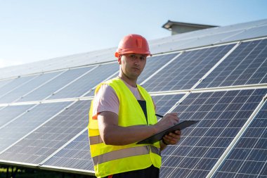 Güneş enerjisi santralinde çalışan üniformalı bir mühendis. Güneş istasyonu geliştirme kavramı