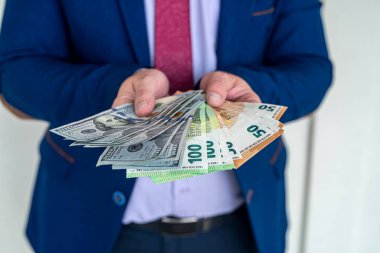 Avro ve dolar tutan mavi takım elbiseli bir adam. yatırım kavramı