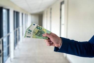 İş adamı takım elbise giyer ve ofiste euro banknotları verir. finans kavramı
