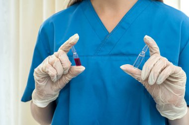 Eldivenli genç ve güzel hemşire bir salgın sırasında elinde aşı tutuyordu. Bir salgın sırasında aşı kavramı