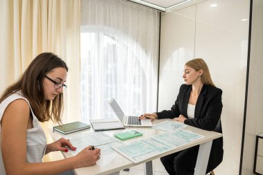 Masada oturmuş vergi formlarını tarif eden iki güzel ofis hanımı. Vergi formu kavramı 1040
