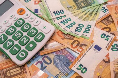 Bir sürü renkli banknot etrafa saçılmış ve güzel düğmeleri olan yeşil bir hesap makinesinin üzerinde duruyor. Hesaplama konsepti. Para kavramı