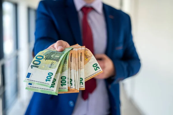 İş adamı takım elbise giyer ve ofiste euro banknotları verir. finans kavramı