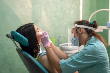 Doktor raporunda dişçi koltuğunda oturan genç kadın.