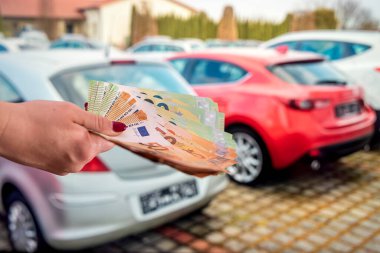 Araba galerisinde elini tutan bir kadın büyük miktarda yeni euro banknotları tutuyor. İş konsepti. Araba iç konsepti