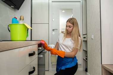 Mutfakta özel eldivenli güzel sarışın bir bezle yüzeyi siliyor. Temizlik kavramı