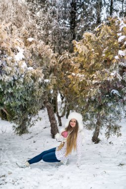 Kış ormanlarında örgü kazaklı, eldivenli ve şapkalı çekici bir kadın.
