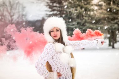 Kar gününde kırmızı duman bombasıyla süveter giyen beyaz bir kadın.