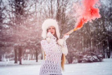 Kar gününde kırmızı duman bombasıyla süveter giyen beyaz bir kadın.
