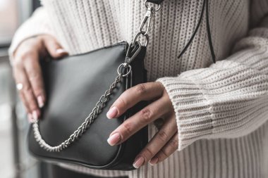 Elinde şık bir bayanla güzel, yeni siyah bir çanta. Moda konsepti. Aksesuar konsepti