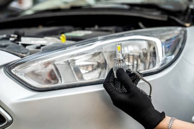 Tamirci, farında kablolar olan modern H7 ampulü kuruyor.