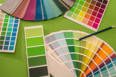 Renkli şablonlar kalem renklerinin kareleri yeşil bir arkaplanda yatar. Tasarım konsepti