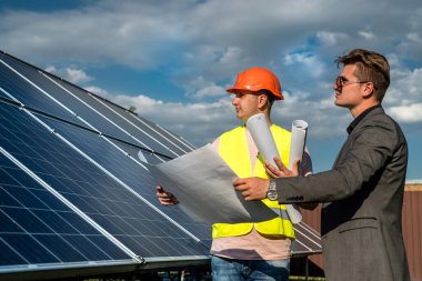 Güneş panellerinin yanında çalışan patrona çalışma planını gösterir.