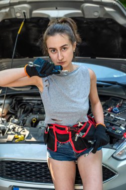 Güzel yalnız kız Forrest Yolu 'nda bozuk arabasını tamir etmek için iş aletlerini tutuyor.. 