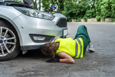 Üniformalı güzel genç bayan tamirci ve özel eldivenler arabanın yanında çalışırken mükemmel bir şekilde başa çıkıyorlar. Tamirci kadın konsepti. Araba tamiri kavramı