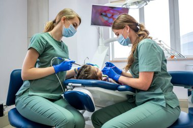 Küçük hasta, dişçiler tarafından ekranda gösterilen kamerayla muayene ediliyor. Çocukların dişlerini kamerayla incelemek.