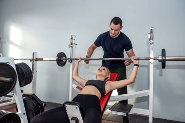 Mutlu, dost canlısı erkek antrenör güzel bir müşteriyle kişisel eğitim yapıyor. Spor salonunda kişisel eğitim kavramı.