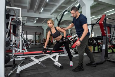 İki neşeli genç kız ve erkek forma girmek için spor salonunda birlikte yürürler. Kilo verme vücut geliştirme kavramı