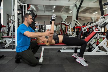 İki genç eğitmen, bir erkek ve bir kadın vücutlarının sağlığını korumak için spor salonunda antrenman yapıyorlar. Spor salonundaki koç kavramı