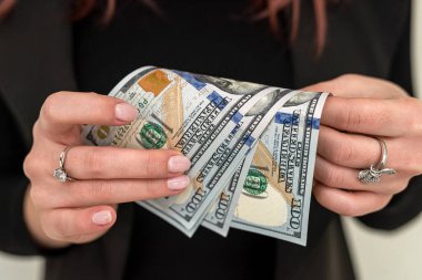 Klasik takım elbiseli güzel bir genç kız elinde yüklü miktarda para tutuyor. İş ve gelir kavramı