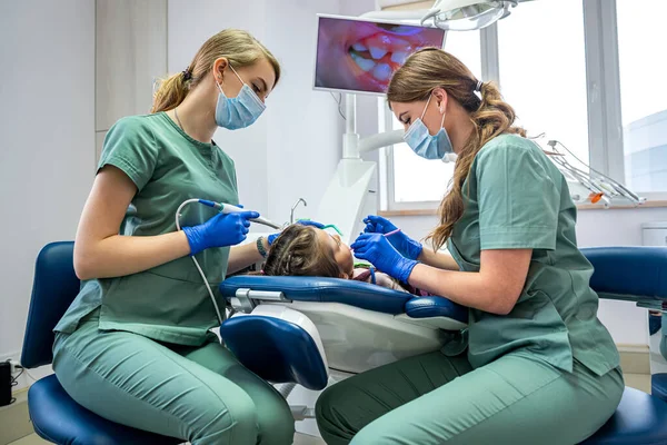 Küçük hasta, dişçiler tarafından ekranda gösterilen kamerayla muayene ediliyor. Çocukların dişlerini kamerayla incelemek.