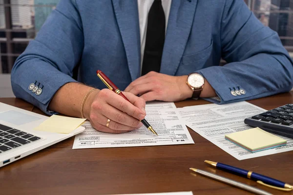 ハンサムな男性ビジネスマンテーブルに座って 米国の税務フォーム1040を記入します 租税形態及び事業者の概念 — ストック写真