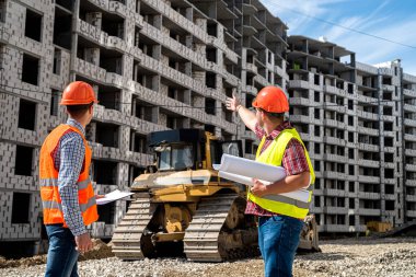 Özel giyimli ve üniformalı iki genç işçi inşaat alanında bir ev inşa etme sürecini tartışıyor. İnşaat konsepti